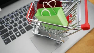 Miniature shopping cart holding paper shopping bags on a laptop keyboard