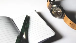 Checklist on paper with a notebook, watch, and pen on a desk
