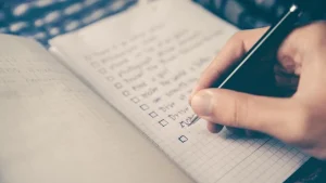 Hand writing a checklist with tick boxes in a spiral notebook
