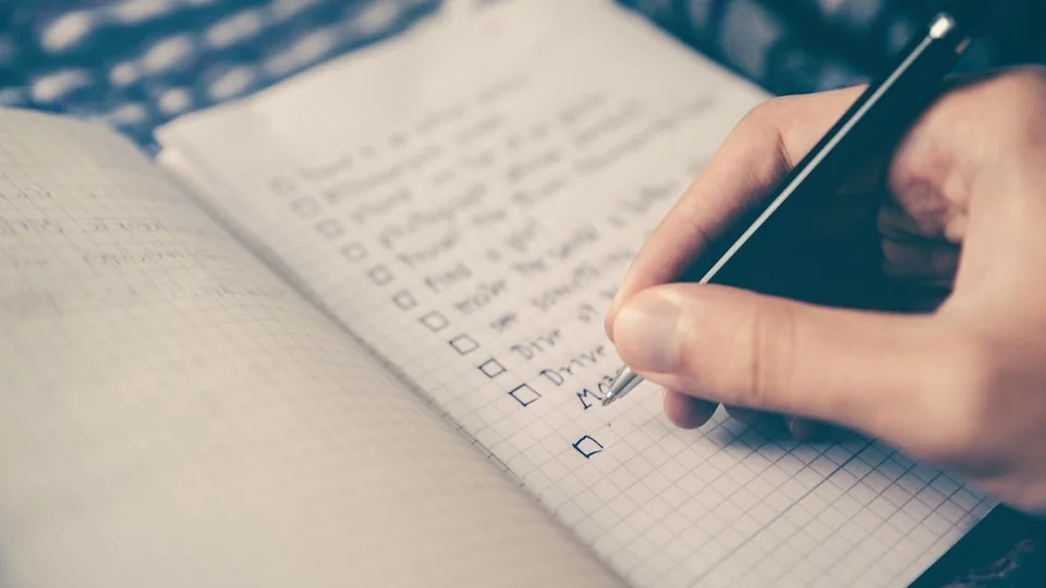 Hand writing a checklist with tick boxes in a spiral notebook