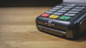 Card payment terminal with colored keys resting on a wooden counter