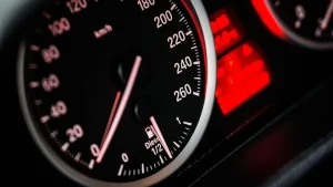 Close-up of a car speedometer glowing red against a dark dashboard