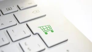 Close-up of a white keyboard with a green shopping cart key for online shopping
