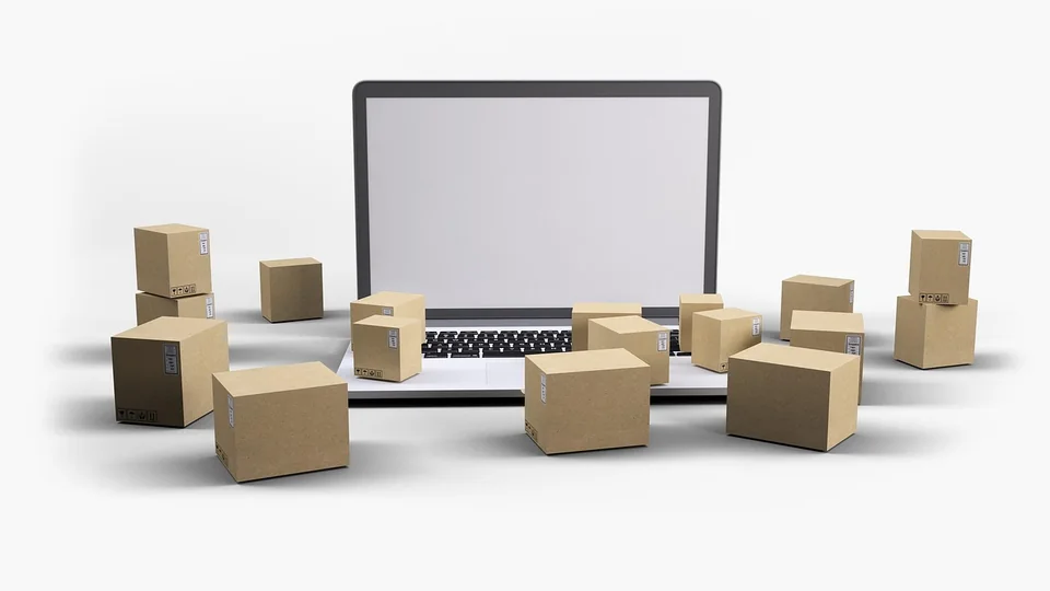 Laptop with a blank screen surrounded by small cardboard shipping boxes